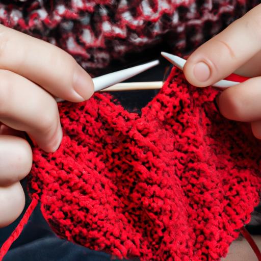 Gần cận hai bàn tay đang đan một hình trái tim bằng sợi len màu đỏ.
